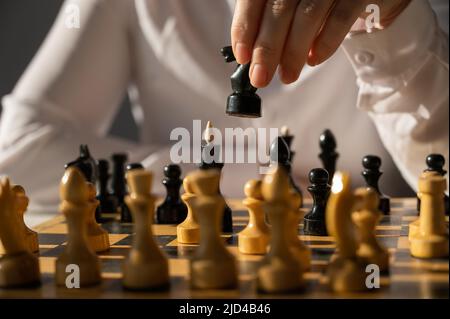Gesichtslose kaukasische Frau im weißen Hemd, die Schach spielt. Stockfoto