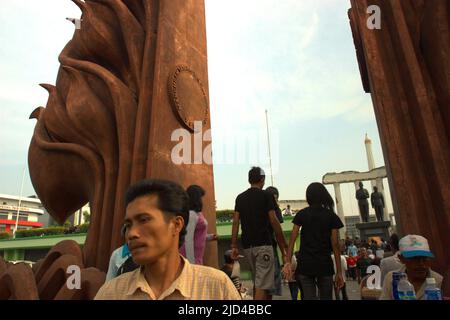 Menschen, die sich in der Nähe des Heroes Monument (10. November Monument) und der Soekarno-Hatta Statue in Surabaya, Ost-Java, Indonesien, Freizeit nehmen. Stockfoto