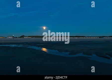 Während der blauen Stunde steigt der Vollmond über dem Strand auf. Besonderes Ereignis namens Supermond: Das nächste, dass der Mond auf die Erde kommt. Stockfoto