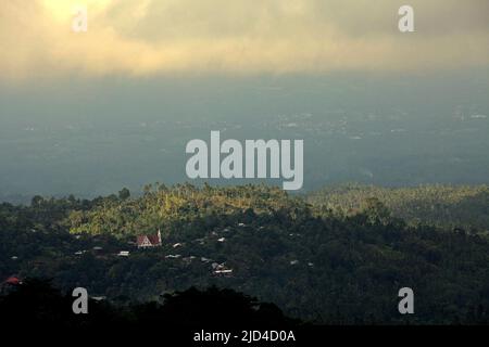 Ein Fernblick auf die Landschaft eines Dorfes, umgeben von Wald- und landwirtschaftlichen Plantagen in Minahasa, Nord-Sulawesi, Indonesien. Stockfoto