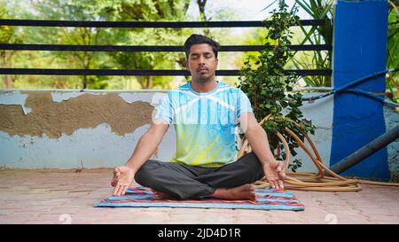 Schöner sportlicher indischer junger Mann, der zu Hause trainiert. Yoga-Pose sitzend. Ruhig und glücklich Stockfoto