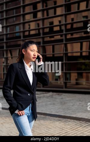 Junge asiatische Geschäftsfrau im Gespräch am Telefon Stockfoto
