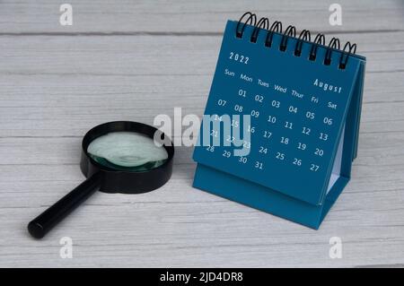 August 2022 blauer Tischkalender auf Holzschreibtisch. Speicherplatz kopieren Stockfoto