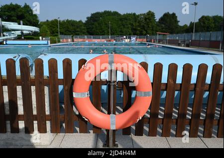 Weener, Deutschland. 18.. Juni 2022. Im Freibad 'Friesenbad', wo bereits am frühen Morgen zahlreiche Badegäste schwimmen, hängt am Beckenrand ein Rettungsschwimmer. Die Wassertemperatur beträgt aufgrund der Fernwärme kontinuierlich 29 Grad. Quelle: Lars Klemmer/dpa/Alamy Live News Stockfoto