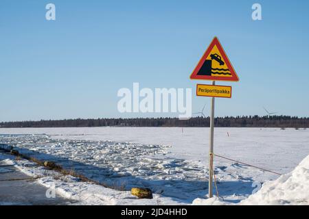 Rovaniemi, Finnland - 21.. März 2022: Ein Schild am Rande eines Anlegekahns, das davor warnt, in das gefrorene Meer zu fallen. Die Schrift auf finnisch bedeutet „Perap Stockfoto