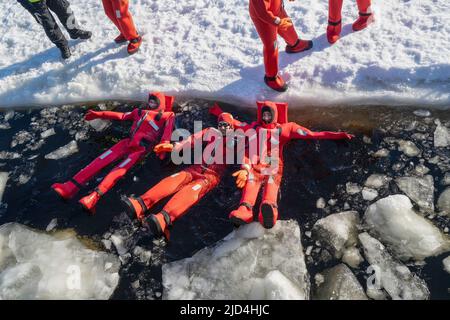 Rovaniemi, Finnland - 21.. März 2022: Eine Gruppe von Touristen schwimmt im gefrorenen Wasser der auftauenden ostsee mit Isolieranzügen. Stockfoto