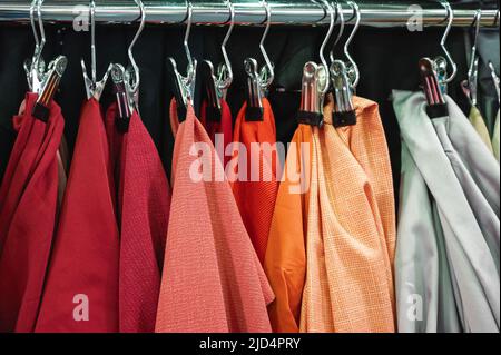 Muster von Stoffen in hellen Farben hängen an der Metallregal-Bar Stockfoto