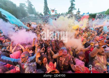 Festivalbesucher werfen auf der Hauptbühne des Belladrum Tartan Hearts Festivals in Inverness, Großbritannien, buntes Pulver Stockfoto