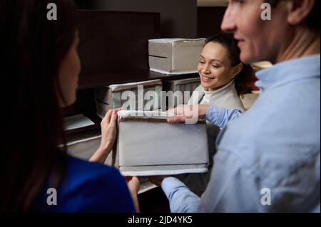 Konzentrieren Sie sich auf einen angenehmen Verkaufsleiter, der Kunden beim Kauf von Bettwäsche eine Probe einer orthopädischen Matratze in einem Möbelgeschäft zeigt. Gesunder Schlaf Stockfoto