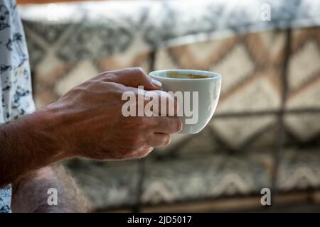 Ein mann, der eine Kaffeetasse mit geringer Schärfentiefe hält Stockfoto