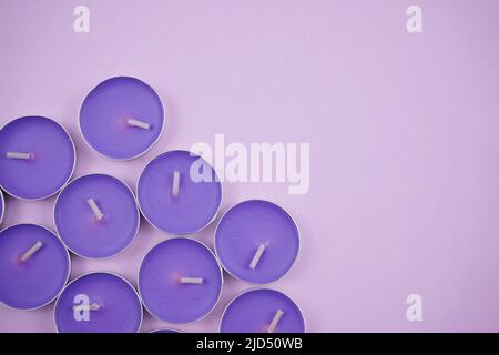 Blauviolette Kerzen auf Pastell. Licht, Massage, Entspannung, Wohlbefinden und minimales Konzept. Stockfoto