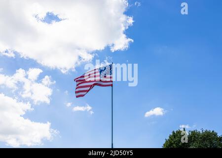 Amerikanische Flagge winkt in einem blau bewölkten Himmel. Die Flagge der USA fliegt Stockfoto