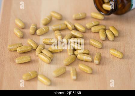 Vitaminpräparatabletten, die aus einer Apothekenplastikflasche verschüttet wurden. Stockfoto