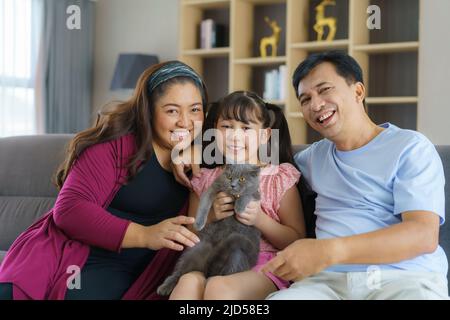 Glückliche asiatische Familie Zeit spielen mit ihrer Katze im Wohnzimmer auf der Couch oder Sofa zu Hause. Stockfoto