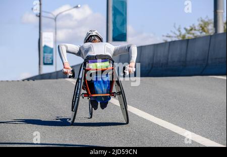Behinderter Athlet auf Rennrollstuhl im Marathonlauf Stockfoto