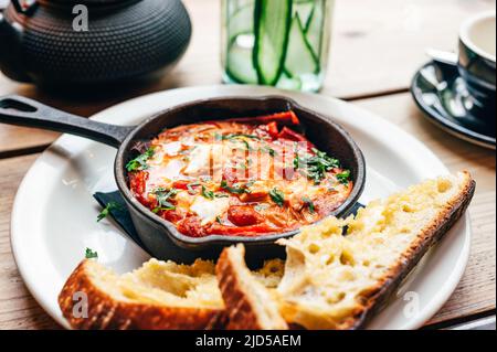 Shakshuka in eiserner Pfanne mit Brot serviert Stockfoto