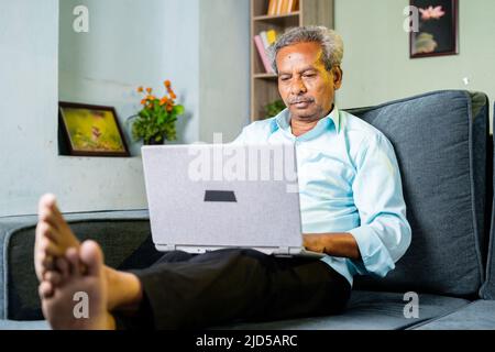 Senior alter Geschäftsmann beschäftigt mit Laptop zu Hause auf dem Sofa - Konzept der Cyberspace, Konzentration und Altersvorsorge Stockfoto