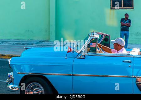 Ein hellblauer Oldtimer mit kleiner kubanischer Flagge trocknet durch die Straße von Alt-Havanna, Kuba Stockfoto