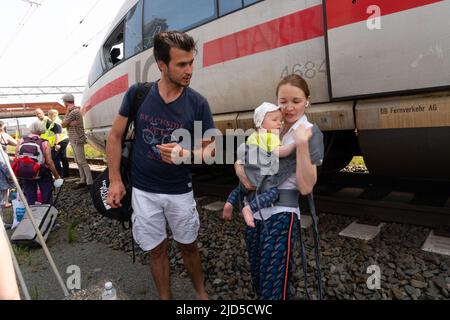 Hertogenbosch, Niederlande. 18 Juni 2022. Eine alleinreisende Mutter mit kleinem Baby erhält von einem anderen Reisenden freundliche Aufmerksamkeit, während Passagiere des kaputten ICE-Zuges (ICE 153) zwischen den Gleisen auf den Austausch des Transports warten. Kredit: Steppeland/Alamy Live Nachrichten. Stockfoto