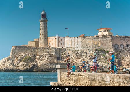 Junge Männer fischen auf dem Malecon mit Havannas berühmter Festung El Morro im Hintergrund Stockfoto