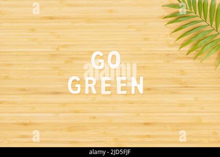 Umweltfreundliches Banner mit Holzbeschriftung Gehen Sie grün auf einem Holzbrett mit Palmblatt und Kopierraum. Zero Waste Konzept mit Logo von Go Green Stockfoto