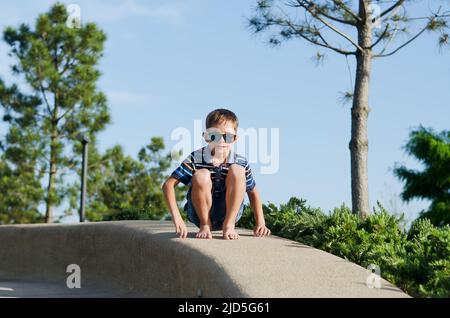 Urlaubskonzept. Kleiner Junge, der Roller reitet, in der Altstadt, Straße zu Fuß. Lachen an einem sonnigen Sommertag. Spaß haben Stockfoto