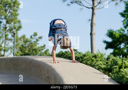 Urlaubskonzept. Kleiner Junge, der Roller reitet, in der Altstadt, Straße zu Fuß. Lachen an einem sonnigen Sommertag. Spaß haben Stockfoto