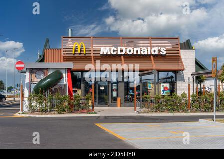 Savigliano, Italien - 16. Juni 2022: McDonald's-Restaurant am wolkenblauen Himmel. Die McDonald's Corporation ist die weltweit größte Kette von Hamburger Fast Foo Stockfoto