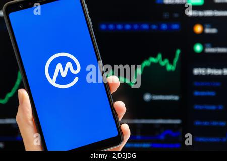 Ukraine, Odessa - Oktober, 9 2021: Hand hält Handy mit Coinmarketcap App läuft auf Smartphone-Bildschirm, Handel Candlestick Chart im Hintergrund. Die weltweit vertrauenswürdigste Kryptowährung-Datenbehörde Stockfoto