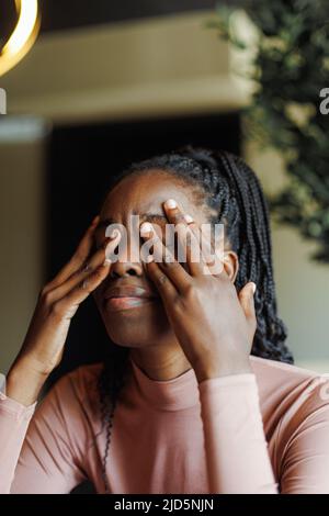 Junge, unglückliche afro-amerikanische Frau mit Dreadlocks, die weinen und die Augen mit Händen in der Nähe des Kaffeehauses bedecken. Depressive schwarze Mädchen leiden, verzweifelt Stockfoto