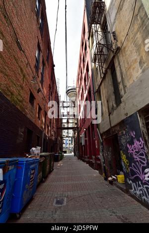 VANCOUVER, BRITISH COLUMBIA, KANADA, 31. MAI 2019: Eine schmale Gasse zwischen farbigen alten Backsteingebäuden und Müllcontainern am Abend im Van Stockfoto