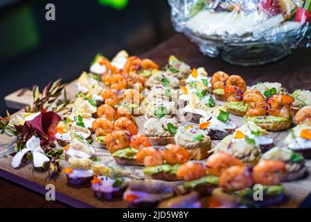 Bruschetta-Set. Frischkäseaufstriche, Garnelen, Mikrogemüse, Aalfilet, Guacamole. Vorspeisen am Büfettisch. Stockfoto