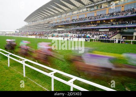 ANMERKUNG DER REDAKTION: FOTO MIT LANGSAMER VERSCHLUSSZEIT AUFGENOMMEN. Läufer und Fahrer kommen in der ersten Runde des letzten Rennens am fünften Tag von Royal Ascot auf der Ascot Racecourse am Grand Stand vorbei. Bilddatum: Samstag, 18. Juni 2022. Stockfoto