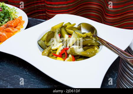 Ein Teller mit in Scheiben geschnittenen Gurkenscheiben, serviert mit Zitronenkeilen und scharfer Chilischote. Buffettisch im Hotelrestaurant. Stockfoto