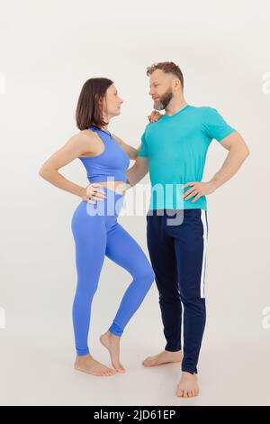 Seitenansicht eines muskulösen Paares aus junger Frau und Mann mittleren Alters, umarmt, Augen treffen, auf weißem Hintergrund stehend. Stockfoto