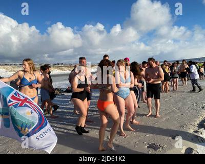 Stanley, Großbritannien. 18.. Juni 2022. Teilnehmer des traditionellen Winterschwimmens stehen zur Verfügung. Dutzende trotzten dem eiskalten Wetter auf den Falklandinseln und sprangen zum Winterschwimmen in den Südatlantik. Quelle: Benedikt von Imhoff/dpa/Alamy Live News Stockfoto