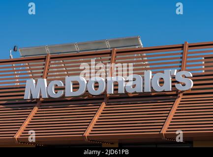 Savigliano, Italien - 16. Juni 2022: McDonald's-Schild am blauen Himmel, McDonald's ist die größte Hamburger-Fast-Food-Kette Stockfoto