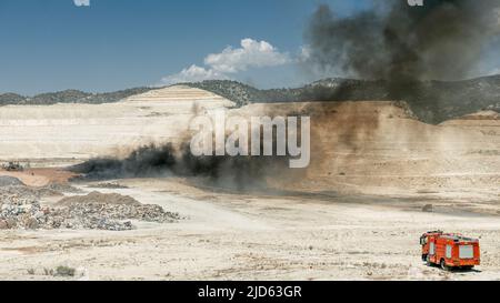 Brandbekämpfung in einer Reifenkippe. Feuerwehrauto und schwarzer Rauch von brennenden Reifen Stockfoto