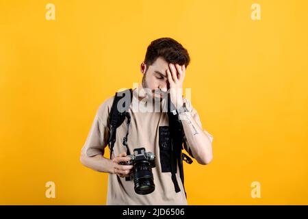 Hübscher junger Mann in legerer Kleidung, der isoliert auf gelbem Hintergrund posiert und gestresst, unglücklich und frustriert ist und Stirn und Holdi berührt Stockfoto