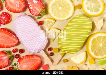 Zwei Eiscremes auf einem Stock - Erdbeere und Zitrone auf beigem Hintergrund. Sommerliche Fruchtdesserts. Stockfoto