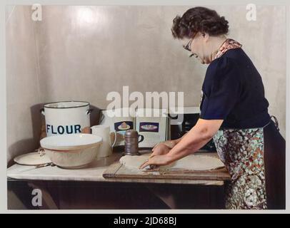 Eine ältere Frau trägt eine blumige Schürze rollt Gebäck für einige zu Hause Backen Colorized Version von : 10088556 Datum: 1947 Stockfoto