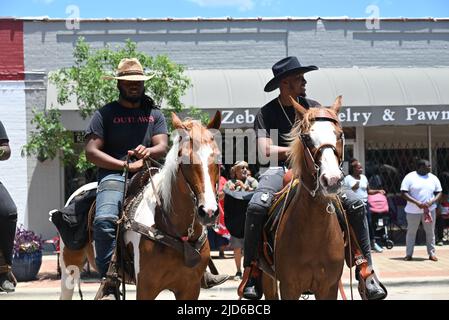 Zebulon, NC, USA, 18.. Juni 2022, afroamerikanische Cowboys ziehen zu Pferd durch die Innenstadt von Zebulon im Rahmen einer wochenlangen Feier der Befreiung von der Sklaverei. Der 2021. Juni ist ein Bundesfeiertag zum Gedenken an die militärische Ankündigung vom 19 1865. Juni, die die Freiheit für versklavte Menschen in Galveston, Texas, proklamiert. Viele Sklaven in Texas waren sich der Emanzipationsproklamation von Präsident Lincoln aus dem Jahr 1863 nicht bewusst, die sie zwei Jahre zuvor aus der Sklaverei befreite, und Sklaven in Galveston waren die letzten, die die Nachrichten hörten. Credit D Guest Smith / Alamy Live News Stockfoto