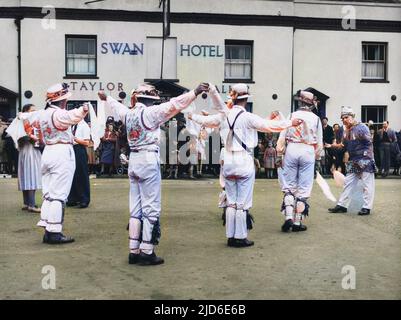 MORRIS DANCING: Thaxted, Essex. Dorfbewohner versammeln sich vor dem Swan Hotel, um einem tanzteam von morris zuzusehen. Einige der Tänzer tragen Westen mit floralen Designs Colorized Version von : 10089750 Datum: 1950s Stockfoto