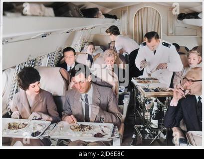 Ein Airline Steward und Air Hostess servieren Fluggästen eine Braten-Mahlzeit. Kolorierte Version von : 10091483 Datum: Anfang 1960s Stockfoto