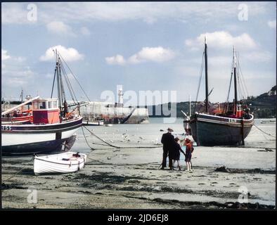 Zwei kleine Jungen halten ihren Großvater in Begleitung, während er sein Gemälde eines Fischtrawlers am Strand in der Nähe des Hafens von St. Ives, Cornwall, beendet. Kolorierte Version von : 10146302 Datum: 1950s Stockfoto