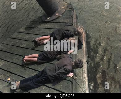 Drei Jungen in Grimsby, Lincolnshire, England - Skipper der Zukunft, die vom Pier der Corporation Bridge über den Fluss Freshney nach Krabben fischen. Kolorierte Version von : 10172009 Datum: 1950s Stockfoto