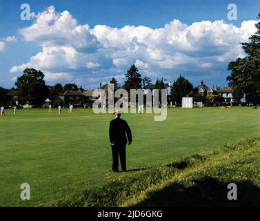 Ein alter Mann mit flacher Kappe steht und sieht sich ein Cricket-Spiel an, das auf Giggs Hill Green, Thames Ditton, Surrey, England, gespielt wird. Kolorierte Version von : 10182728 Datum: 1950s Stockfoto