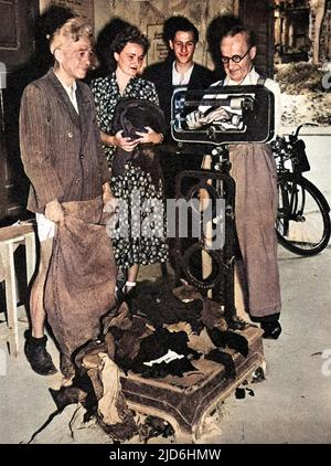 Foto von mehreren West-Berliner Bürgern, die ihre alten Wollkleidung in ein Second-Hand-Bekleidungsdepot bringen, Berlin, August 1948. Die Kleidung wurde gewogen, dann wurden Genehmigungen für den Kauf neuer Kleidung mit einem entsprechenden Gewicht erteilt. Die sowjetische Blockade West-Berlins bedeutete, dass der Mangel an allen Verbrauchsmaterialien unvermeidlich war. Zwischen April 1948 und Mai 1949 verhängte Josef Stalin, der Führer der UdSSR, eine Landblockade für Lieferungen von Westeuropa nach West-Berlin. Als Reaktion darauf organisierten die britische und die amerikanische Regierung eine riesige Luftbrücke, um Lebensmittel und andere lebenswichtige Güter zu liefern Stockfoto