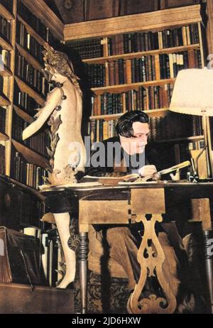 Salvador Dali (1904 - 1989) sitzt an einem Schreibtisch für eine Bibliotheksstudie des surrealistischen Künstlers als Autor. Zu dieser Zeit arbeitete er an seinem Buch "das geheime Leben von Salvador Dali". Als er nach der Anwesenheit der Statue gefragt wurde, sagte er: 'Nur um die Leute dazu zu bringen, Fragen zu stellen.' Kolorierte Version von: 10224362 Datum: 1941 Stockfoto