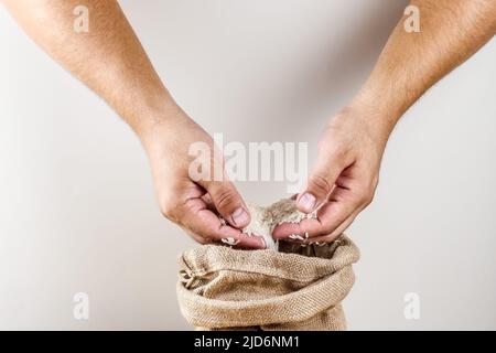 Hände halten Reis, Beutel mit Reis Stockfoto